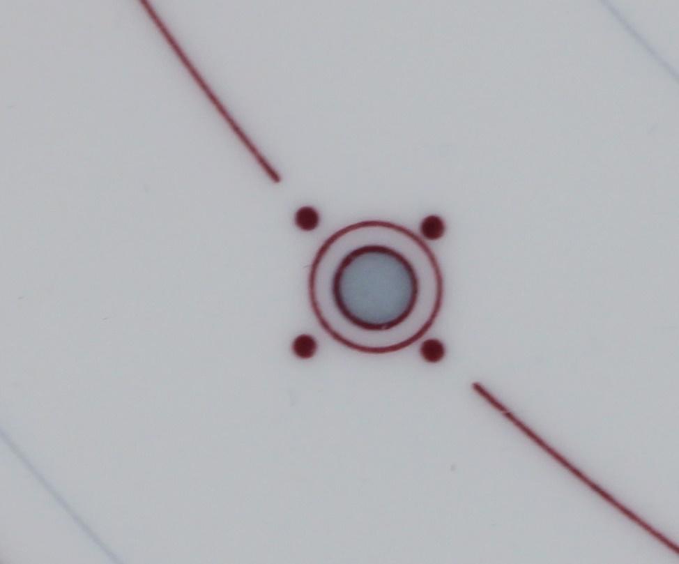 Dritte Detailansicht des Aragon Musters: Im Fokus ein blau/grauer Punkt. Umrandet von einer dunkelroten Linie. Ein weiterer Kreis geht um den inneren Kreis. Aussen sind 4 dunkelrot gefüllte Punkte um den Kreis angeordnet. Eine dunkelrote Linie geht um den Teller.